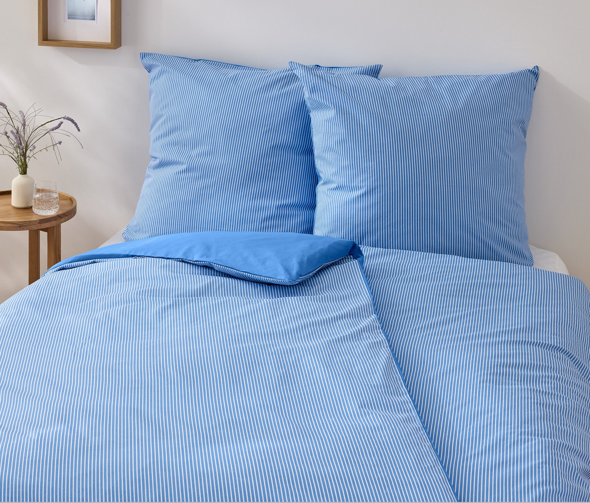 Ein blau-weiss gestreiftes Renforcé-Bettwäsche-Set in Normalgröße liegt auf einem Bett.