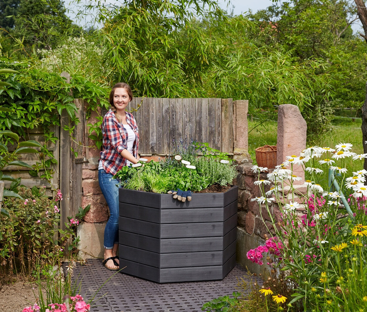 Eine Frau steht neben einem mit Pflanzen und Blumen bepflanzten Garantia Ergo Hochbeet »L75«.