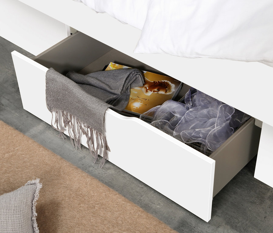 Geöffnete Schublade des weißen rauch Betts »Aditio Beds«, 140 cm mit Polsterkopfteil, gefüllt mit Kleidung.