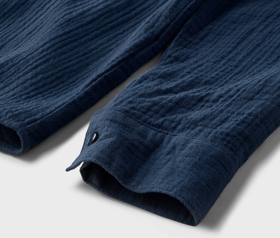 Detailansicht einer marineblauen Musselin-Bluse mit Knopf.