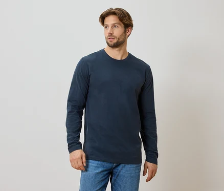 Mann mit Bart trägt ein marineblaues Langarmshirt und Jeans.