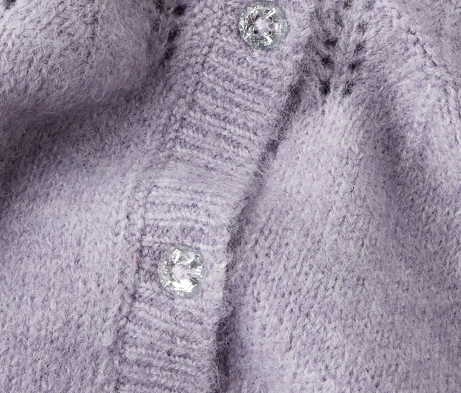 Nahaufnahme einer lila Strickjacke mit zwei silbernen Knöpfen.