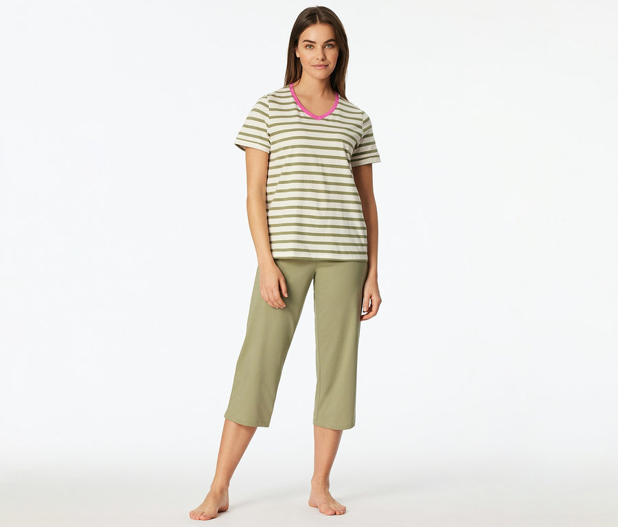 Frau steht barfuß, trägt ein gestreiftes T-Shirt mit pinkem Ausschnitt und olivfarbene Dreiviertelhosen.