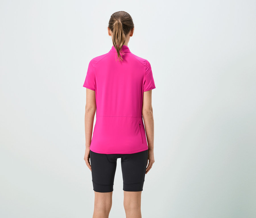Rückansicht einer Frau mit Pferdeschwanz, die ein pinkes Kurzarmtrikot und schwarze Shorts trägt.