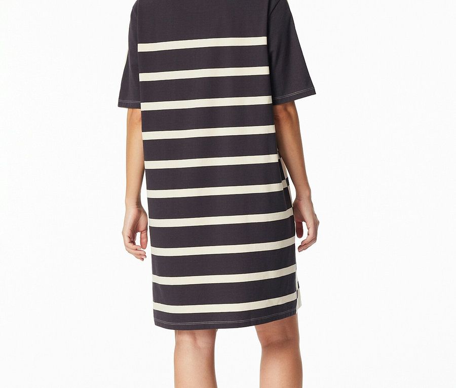 Eine Frau steht mit dem Rücken zur Kamera und trägt ein dunkelgraues SCHIESSER Nachthemd mit cremefarbenen Querstreifen.