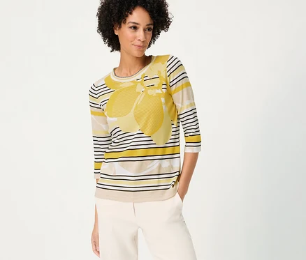 Frau mit beigen Hosen und Olsen 3/4-Shirt mit gelbem Muster und Streifen.