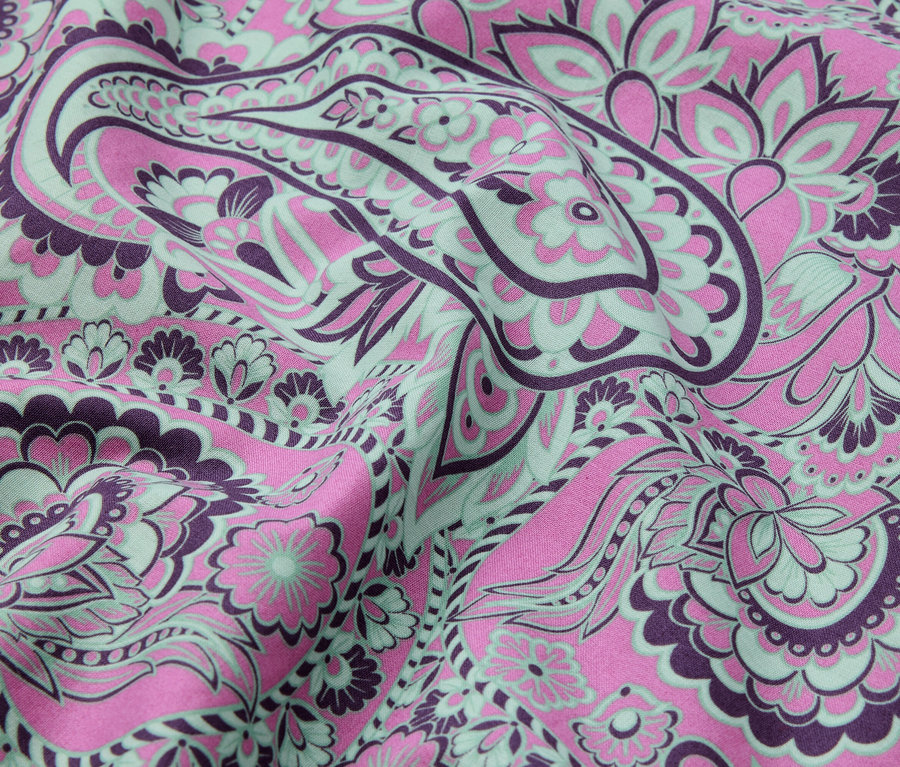 Nahaufnahme von Stoff mit einem abstrakten Blumenmuster in Rosa, Lila und Mintgrün.