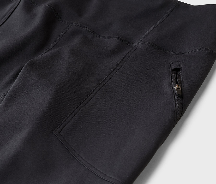 Nahaufnahme einer schwarzen Sporthose oder Leggings mit Reißverschlusstasche an der Seite und sichtbaren Nähten.