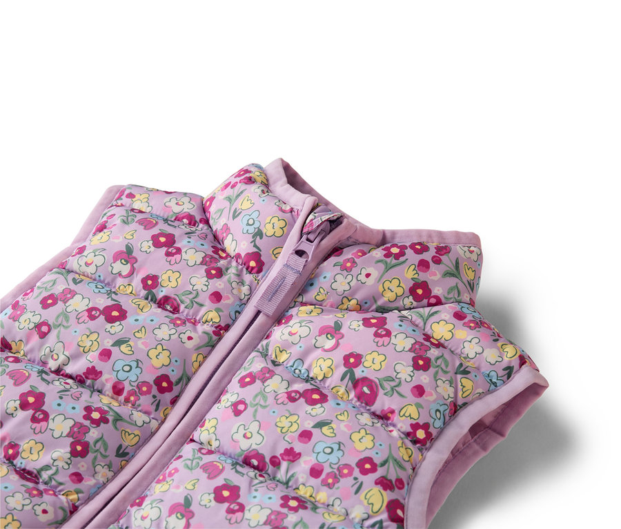 Nahaufnahme einer lila, gesteppten Weste mit Blumenmuster und Reissverschluss.