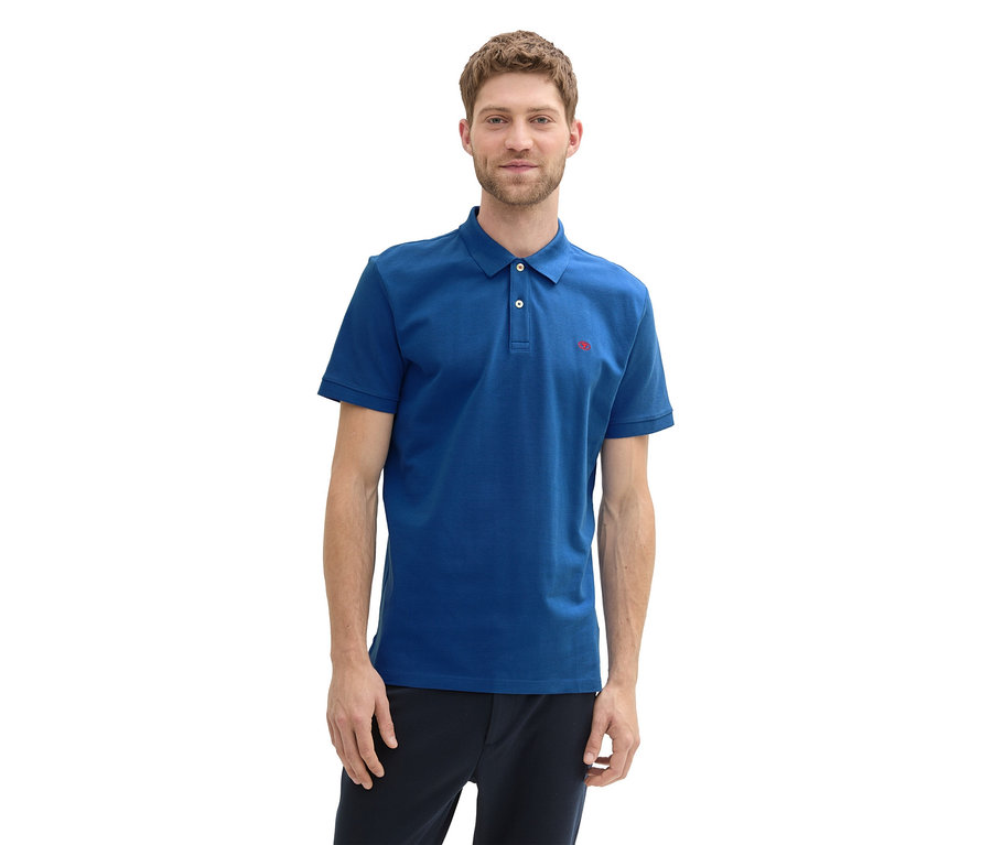 Mann trägt ein Tom Tailor Piqué Poloshirt in Advanced Blue und dunkle Hose.