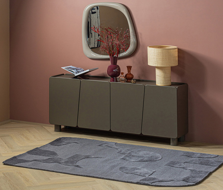 Dunkelgraues Sideboard mit Spiegel, Lampe und Deko vor rosa Wand, dazu grauer WOOOD Teppich Livo auf Holzboden.