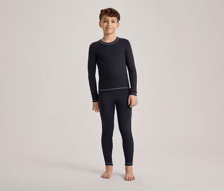 Ein Junge steht barfuß und trägt ein dunkelblaues Langarmshirt und passende Leggings mit hellen Nähten.