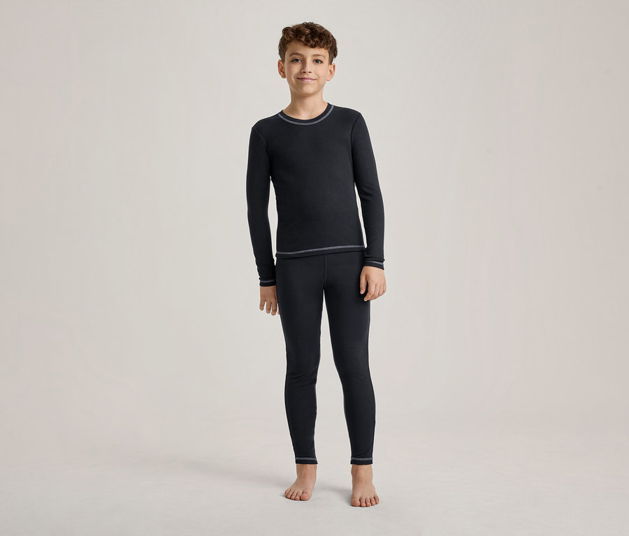 Ein Junge steht barfuß und trägt ein dunkelblaues Langarmshirt und passende Leggings mit hellen Nähten.
