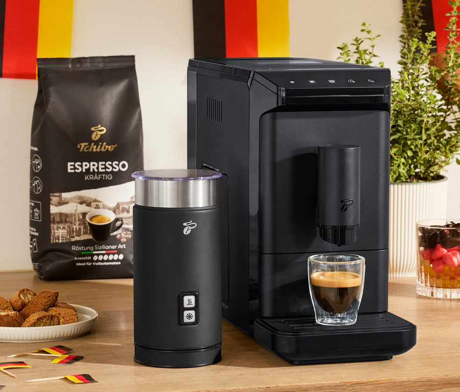 Ein »Esperto mini« Kaffeevollautomat, ein schwarzer, elektrischer Milchaufschäumer und zwei doppelwandige Espresso Gläser stehen auf einem Tisch.