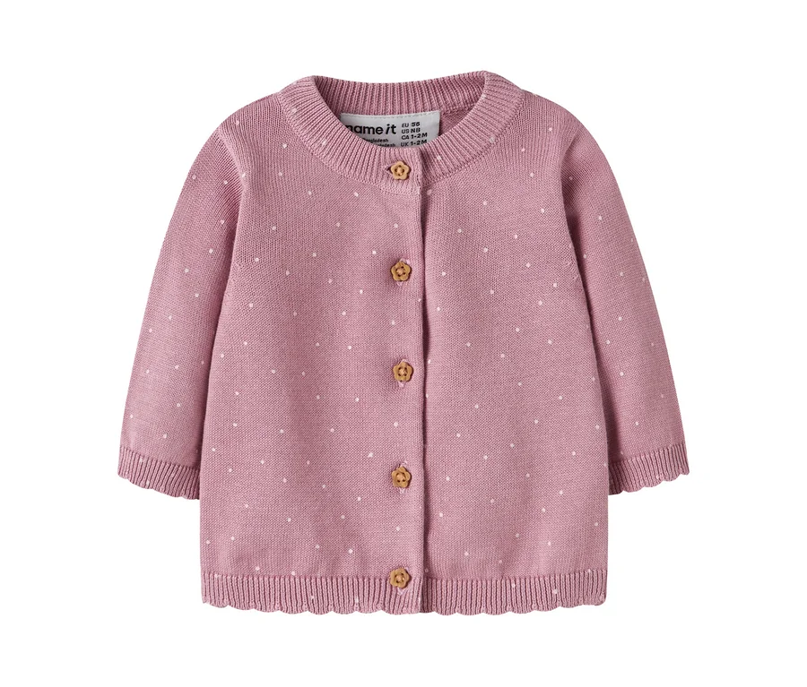 Rosa gestrickte Baby-Strickjacke mit weißen Punkten, Rundhalsausschnitt und langen Ärmeln. Sie hat fünf hellbraune, blumig geschnitzte Knöpfe und einen gerippten Saum mit Wellenkante. Ein "name it"-Markenetikett ist sichtbar.