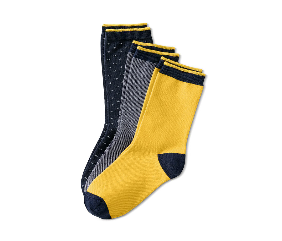 Drei Paar Socken liegen auf einem weißen Hintergrund. Ein Paar ist dunkelblau mit kleinen weißen Punkten, eines grau gestreift und eines gelb mit dunkelblauer Spitze. Alle Socken haben einen dunkelblauen Rand. 3 Paar Socken
