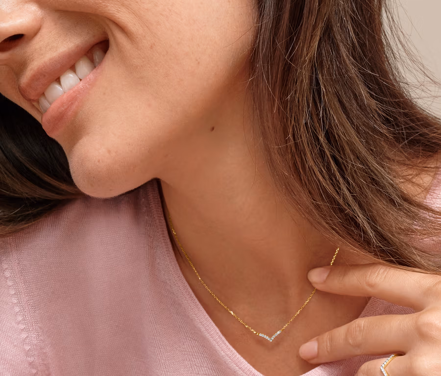 Frau mit Gold-Kette V-Anhänger Zirkonia und Gold Ring V Zirkonia.