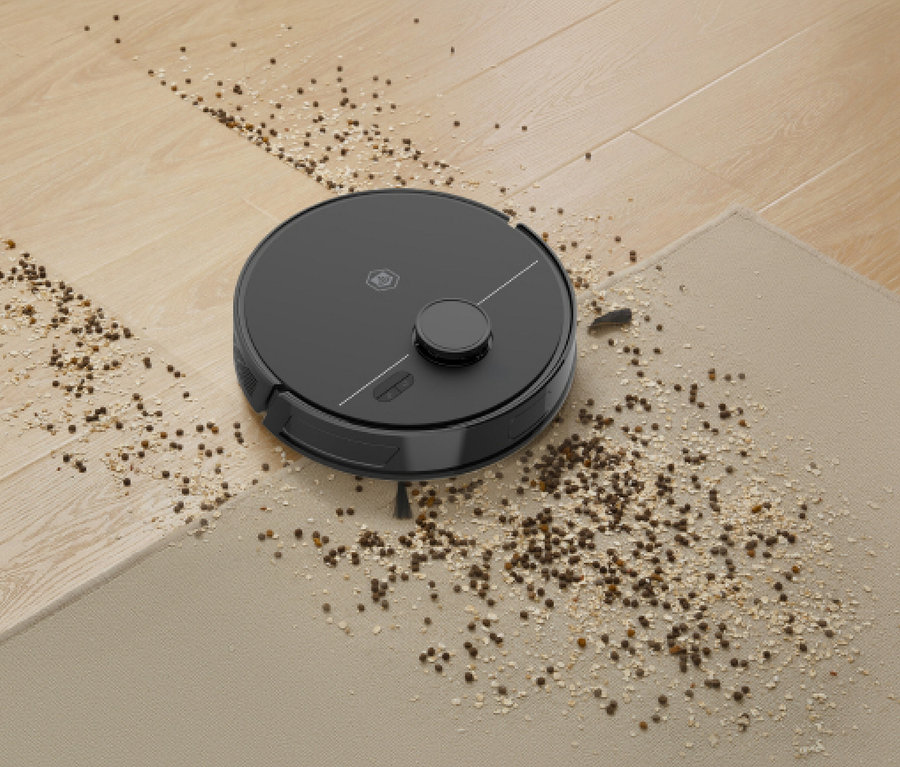 Ein schwarzer Roboterstaubsauger steht auf einem Boden, der teilweise aus hellem Holz und teilweise aus beigem Teppich besteht, umgeben von Schmutz.