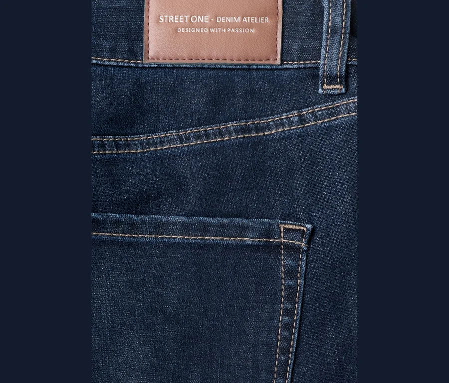 Dunkelblaue Street One Jeans mit hellbraunen Nähten und einem braunen Lederpatch mit „STREET ONE - DENIM ATELIER“ Aufschrift am Bund.
