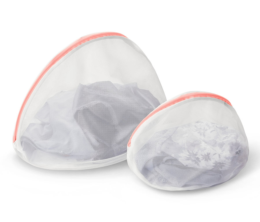 Zwei weiße Wäschenetze mit rosa Reißverschluss, eines größer und eines kleiner, gefüllt mit Kleidung.
