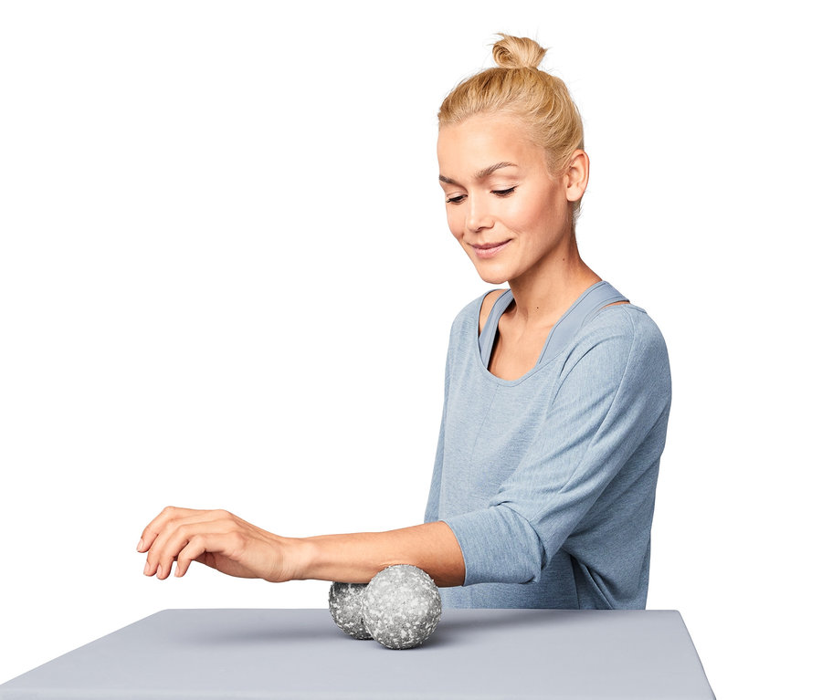 Frau benutzt Duo-Faszienmassageball auf ihrem Unterarm.