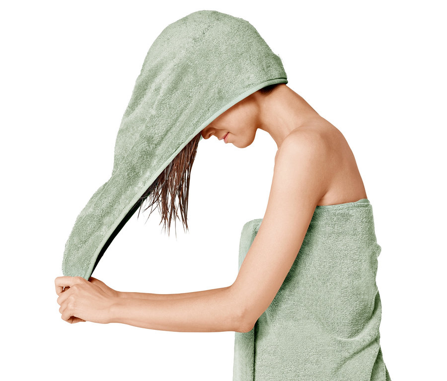 Frau trocknet ihr Haar mit einem grünen Turban-Handtuch.