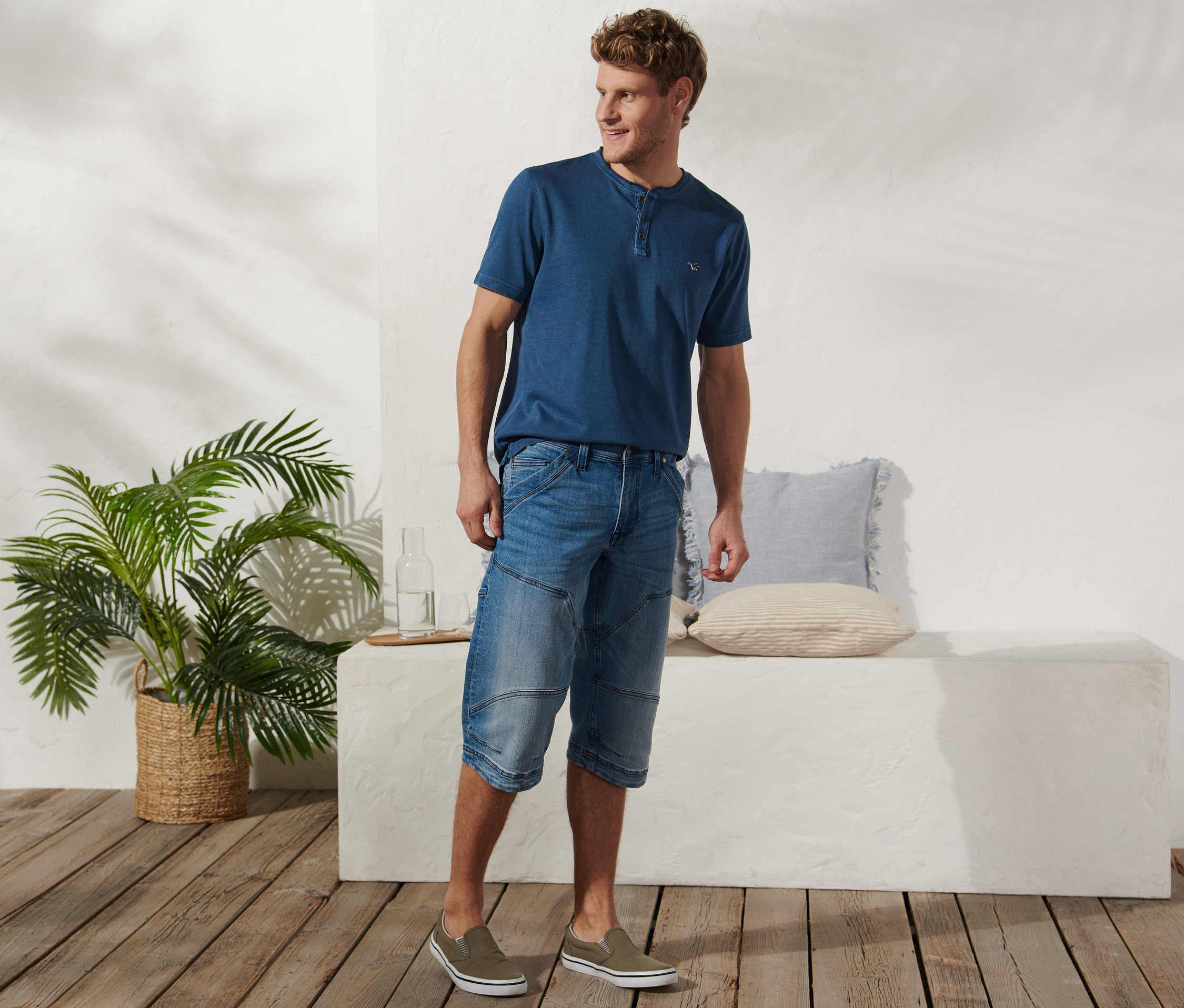 Ein Mann posiert in Jeans-Bermuda-Shorts von Mustang und einem T-Shirt.