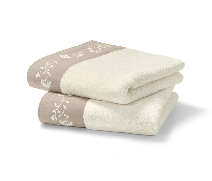 Zwei beige Premium-Handtücher liegen gefaltet übereinander.