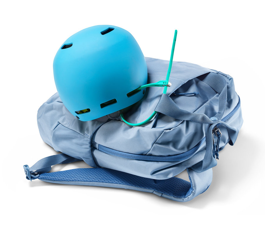 Blauer Helm liegt auf einem blauen Rucksack mit einem Kabelbinderschloss.