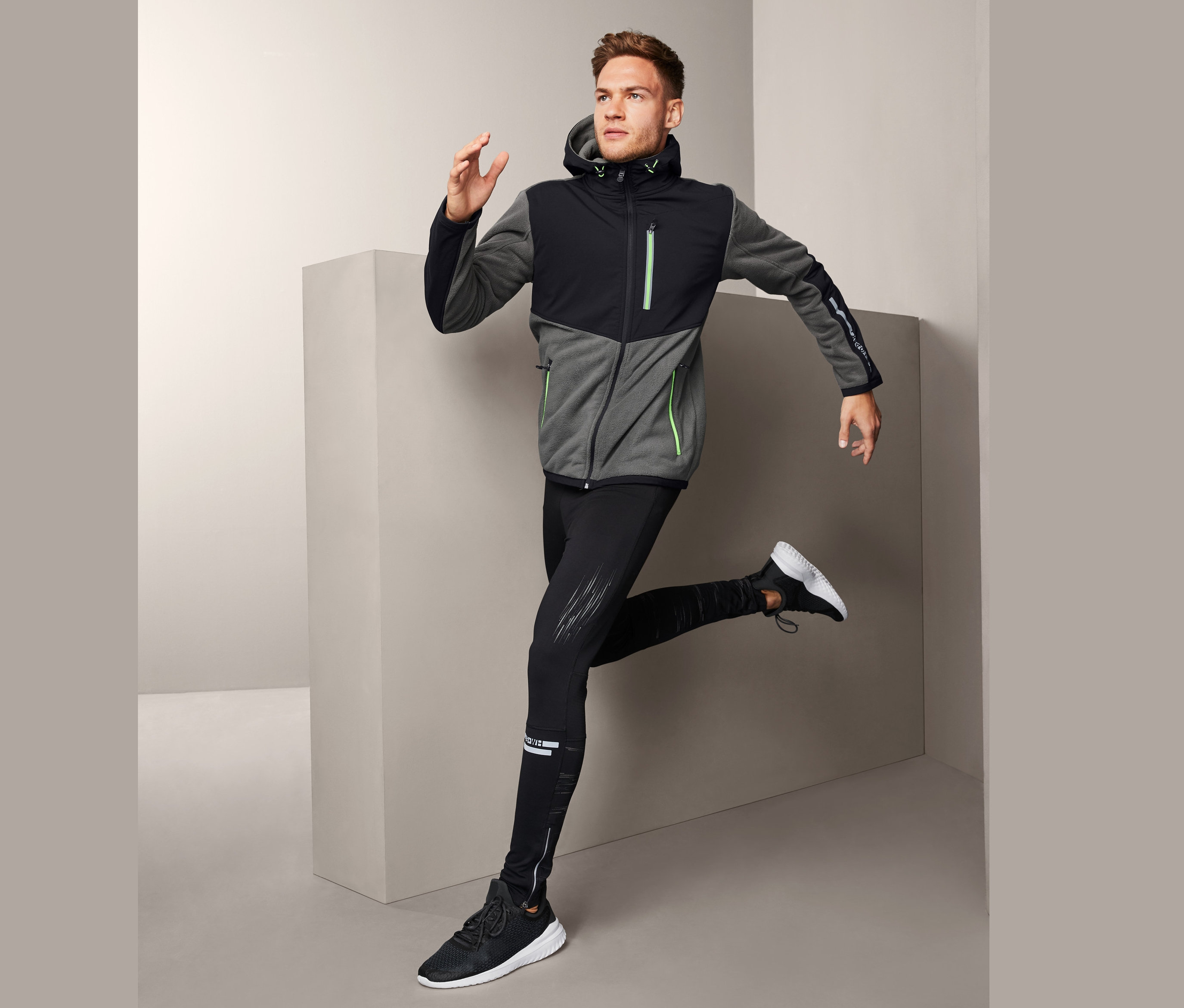 Mann in Hybrid-Fleecejacke posiert in Laufposition.