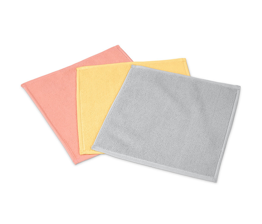 Drei Microfaser-Kosmetiktücher in Rosa, Gelb und Grau liegen auf einem weißen Hintergrund.