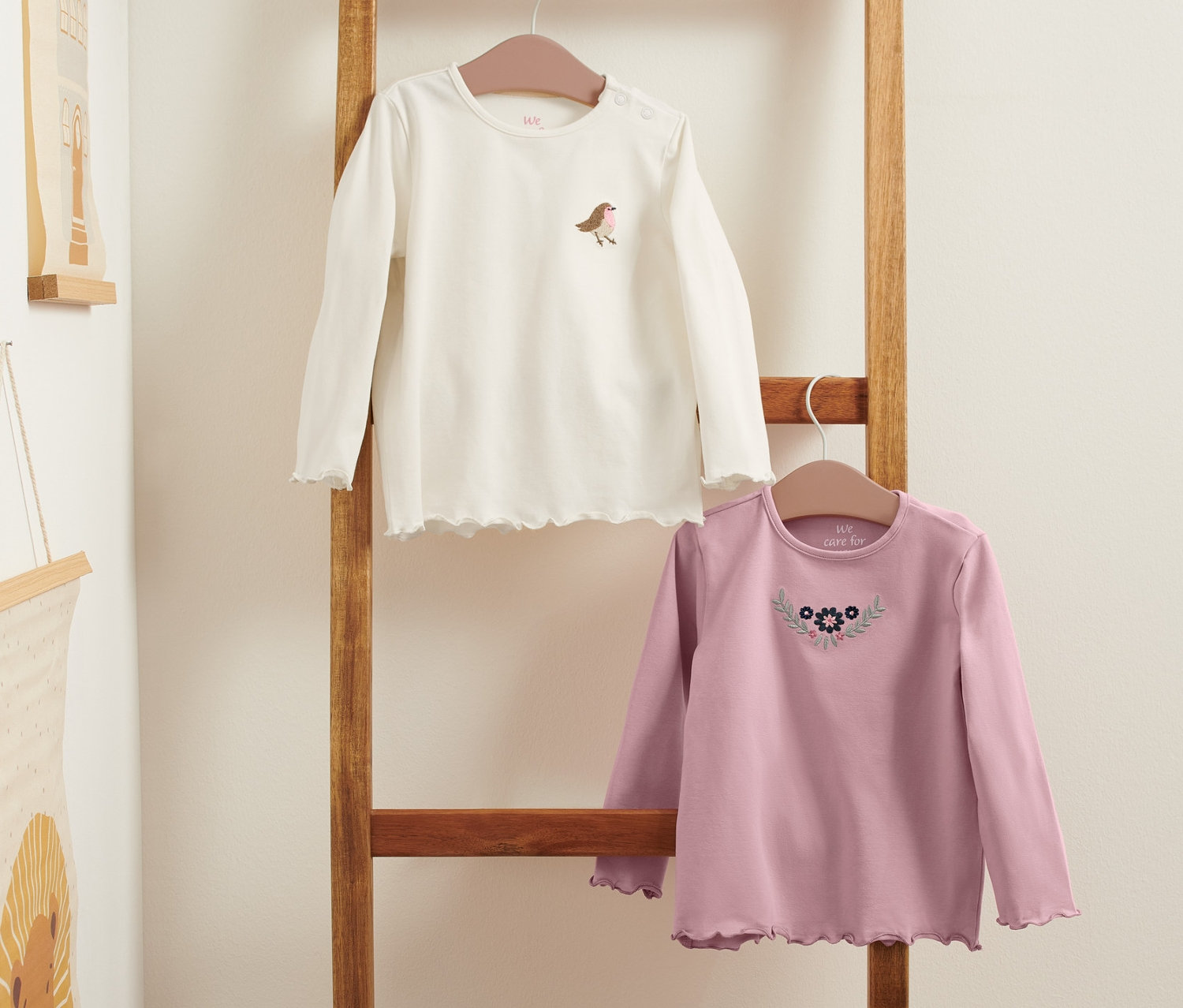 Zwei Langarmshirts hängen auf einer Holzleiter.