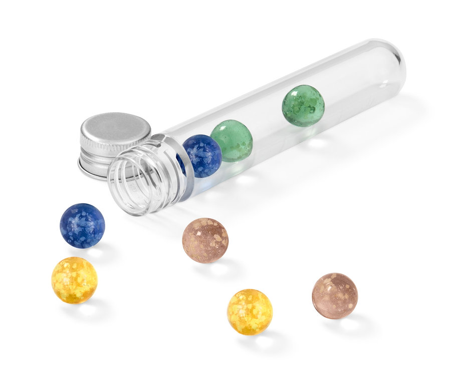 Ein durchsichtiges Reagenzglas liegt auf der Seite und enthält Leuchtmurmeln in verschiedenen Farben, weitere Murmeln sind daneben verstreut.