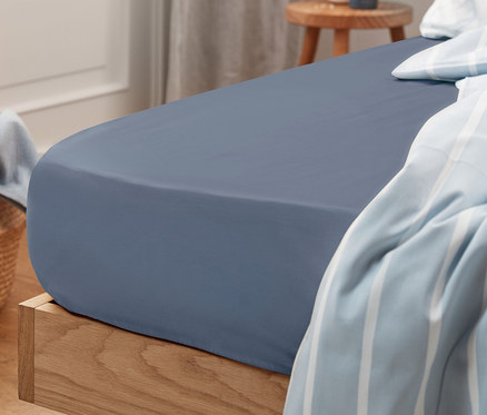 Blaues Jersey-Spannbettlaken in Normalgröße auf einem Bett.