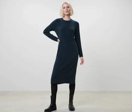 Frau posiert in geripptem, dunkelblauem Strickkleid.