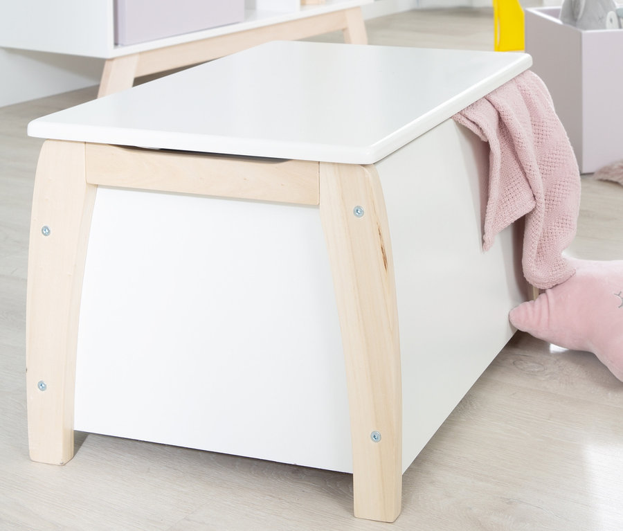 Weiße roba Spielzeugtruhe mit Holzfüßen und einer rosa Decke, die seitlich liegt.