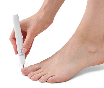 Frau benutzt ein Maniküre-und-Pediküre-Gerät auf ihrem Zehennagel.