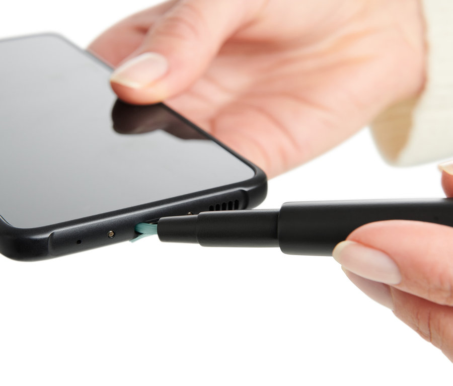 Frau reinigt den Ladeanschluss eines Smartphones mit einem Multifunktions-Reinigungsstift.
