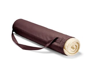 Eine zusammengerollte Schurwoll-Yogamatte in einer bordeauxfarbenen Hülle mit Riemen.