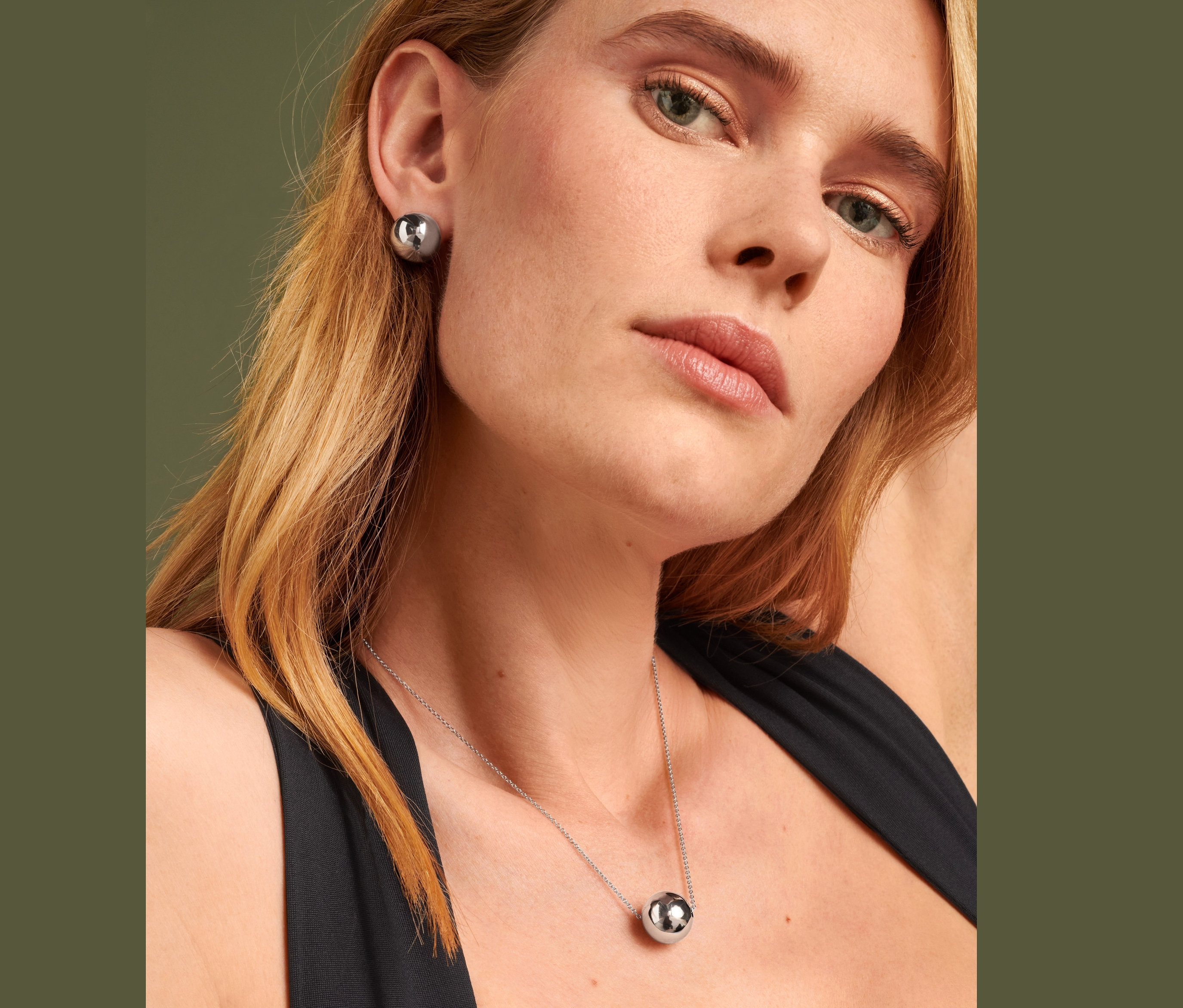 Blonde Frau trägt Ohrstecker Globe und Kette Globe.