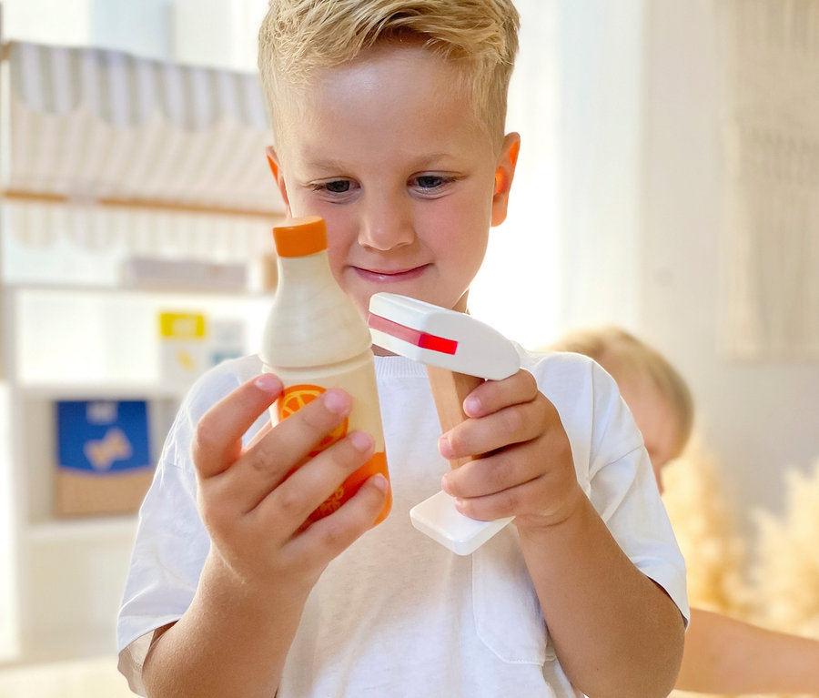 Ein Junge hält eine Holzspielzeugflasche und einen Scanner aus dem small foot Back-, Gefrier- und Kühlwaren-Set »fresh« in der Hand.