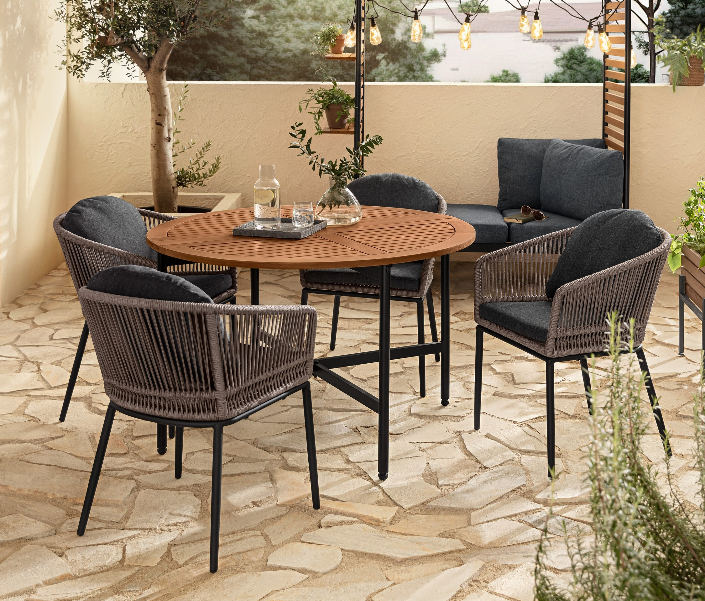 Terrassensitzgruppe mit Ausklapptisch »Elin«, Dining-Sesseln mit Textilgeflecht und Outdoor Lounge »Elin«. Über dem Tisch hängt eine LED-Filament-Lichterkette.