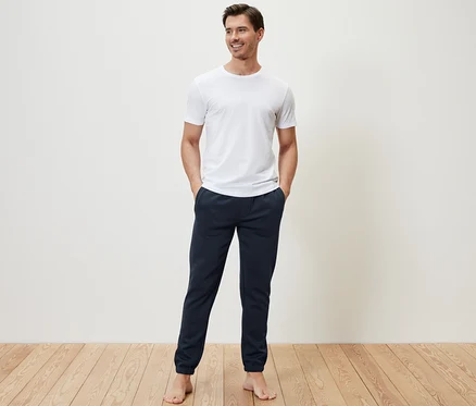 Mann steht mit Händen in den Taschen der Sweathose.