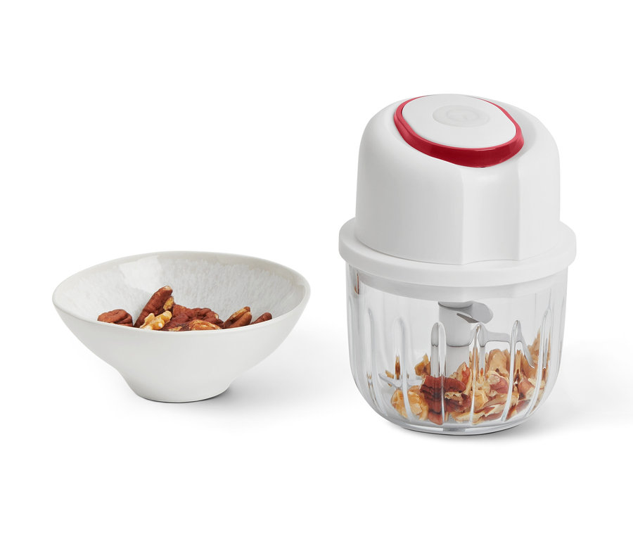 Eine Schale Nüsse neben einem kabellosen Multizerkleinerer mit gehackten Nüssen.
