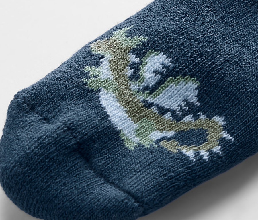 Detailaufnahme einer blauen Babysocke mit einem gezeichneten Drachen.