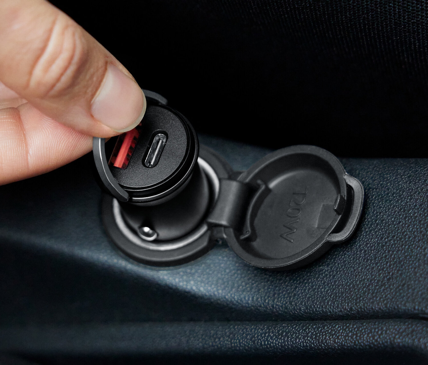 Eine Hand steckt ein KFZ-Schnellladegerät in eine Steckdose.