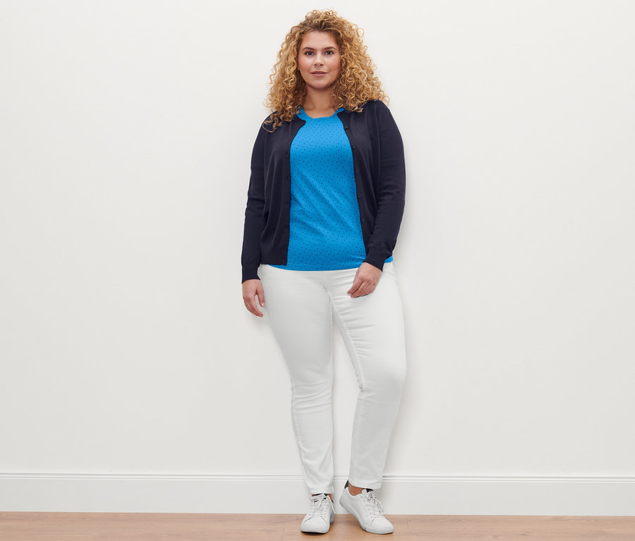 Frau posiert mit einem gepunkteten T-Shirt, einer cremeweißen Colored Denim »Fit Emma« und einem Feinstrick-Cardigan.