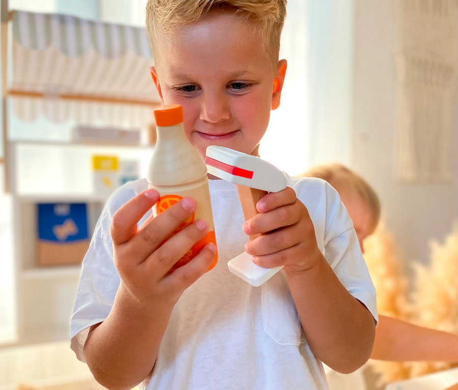 Junge hält hölzerne Spielzeugflasche und Scanner in der Nähe von small foot Kaufladen kompakt »fresh«.