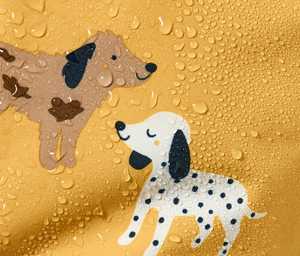 Detailansicht eines gelben Regen-Einteilers mit Cartoon-Hunden und Wassertropfen.