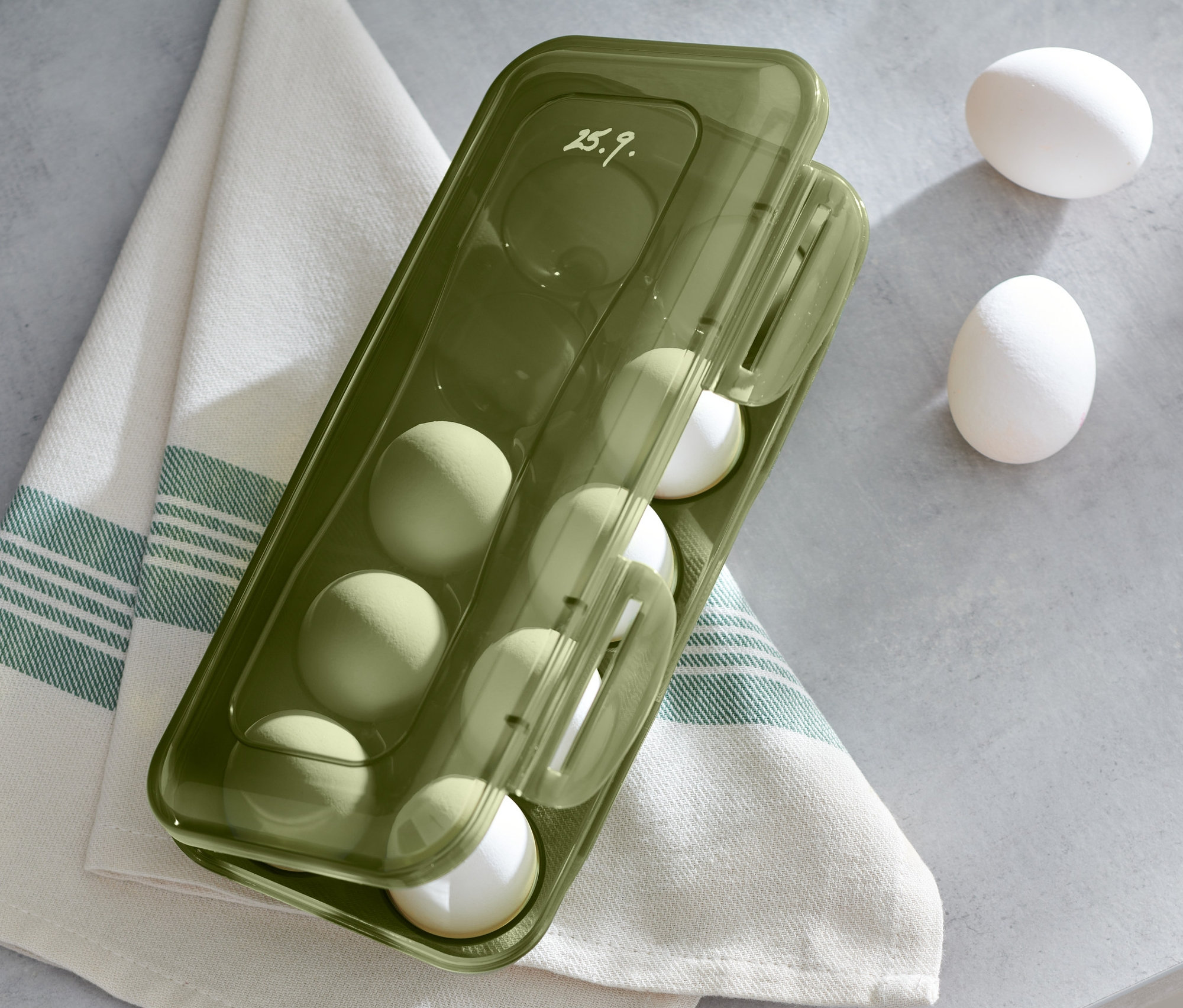 Ein grüner Eier-Aufbewahrungsbox mit Eiern auf einem Leinentuch.